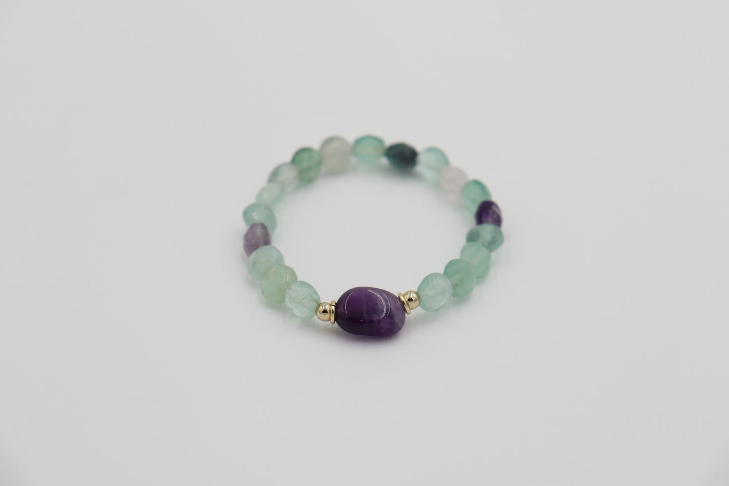 Soft fluorite beads — associated with focus and mental clarity — surround a central oval amethyst, the stone of protection and spiritual strength. Together, they represent balance between mind and heart. Designed to honor the woman who leads with wisdom, calm confidence, and inner alignment.