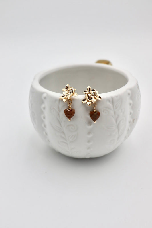 A celebration of strength and passion. Deep red jasper hearts — known for grounding and vitality — are paired with a delicate gold-plated flower, symbolizing growth, love, and beauty. A piece to wear your heart boldly.