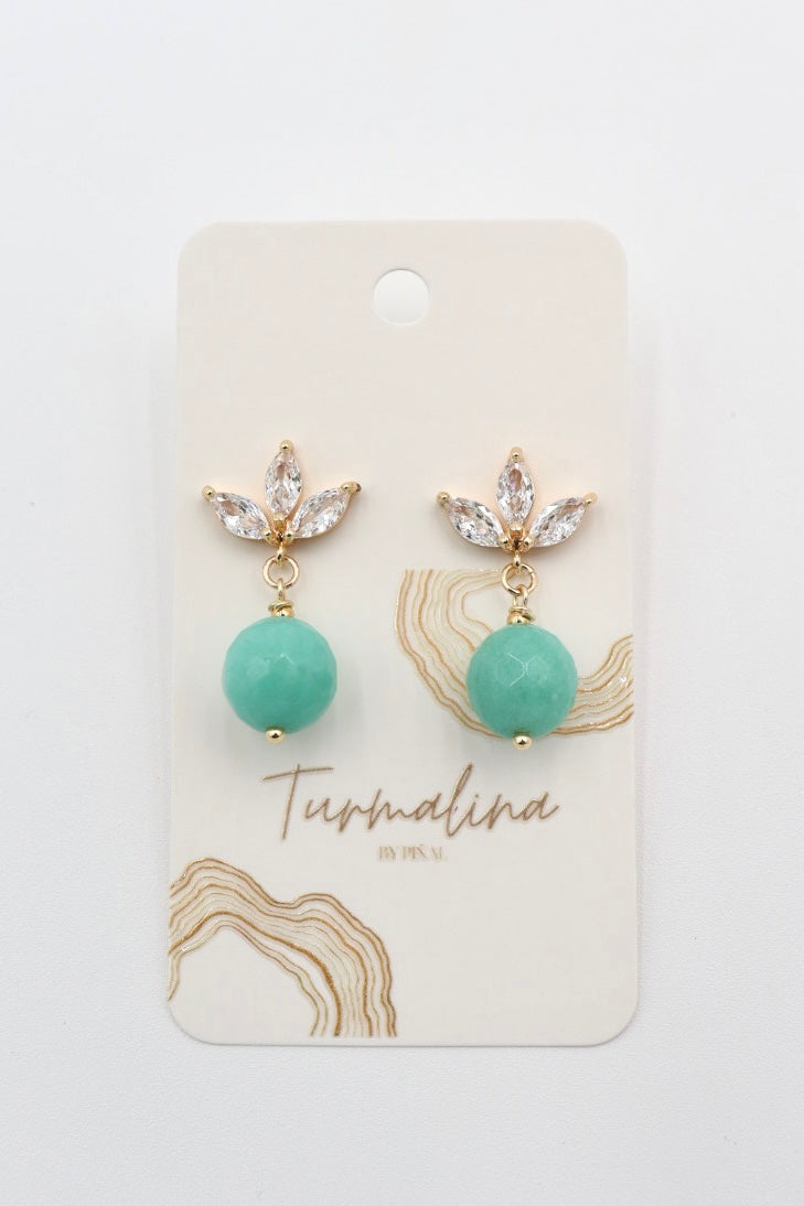 A pair of gold drop earrings with clear rhinestone leaf clusters and round mint green turquoise  amazonite beads, displayed on a cream-colored jewelry card labeled 'Turmalina by Pinal'.