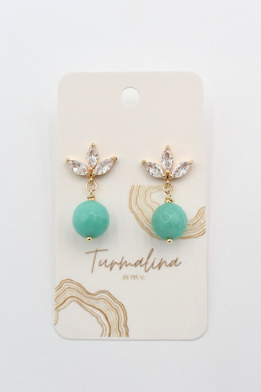 A pair of gold drop earrings with clear rhinestone leaf clusters and round mint green turquoise  amazonite beads, displayed on a cream-colored jewelry card labeled 'Turmalina by Pinal'.